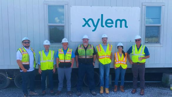 People in PPE stand before a Xylem sign