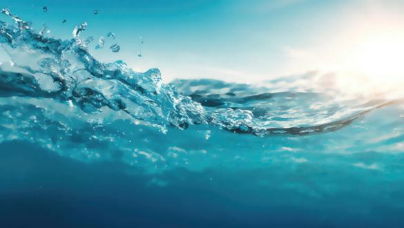 Close-up view of the ocean's surface, showing clear blue water and sunlight reflecting on the waves.