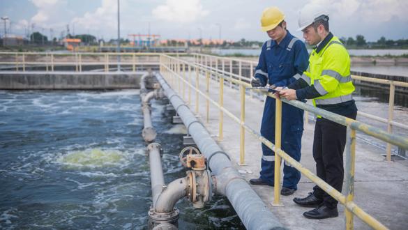 An expert inspector and technicians are seriously checking the water quality in the treatment pond and the operation of the water filter system of the treatment pond.