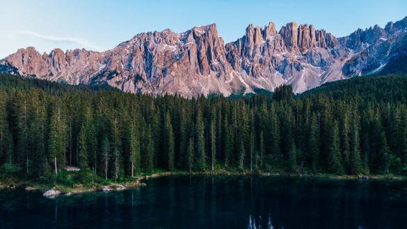 Picturesque peaks of Dolomites mountains in reflection of crystal clear pond surrounded by coniferous forest. Lake of Caresse in Italy. Scenic place and famous touristic destination. Primeval nature; Shutterstock ID 1149951575; purchase_order: Xylem; job: ; client: ; other: 