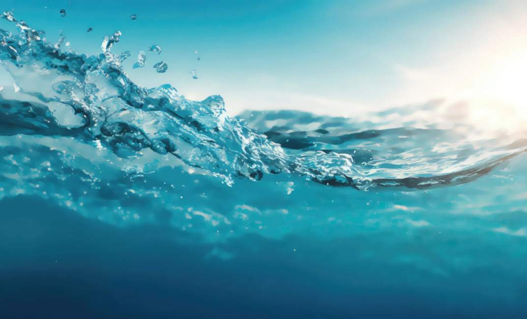 Close-up view of the ocean's surface, showing clear blue water and sunlight reflecting on the waves.